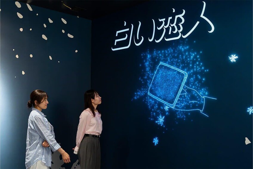 Two people looking at a digital display with a blue background and a glowing square with snowflakes. 5