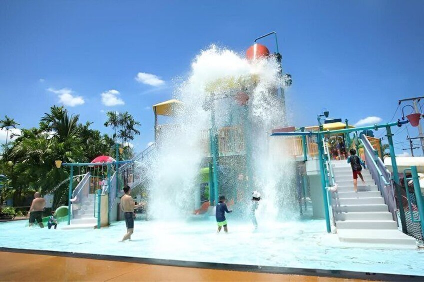 A water park with a large water fountain, a slide, and a pool. 4