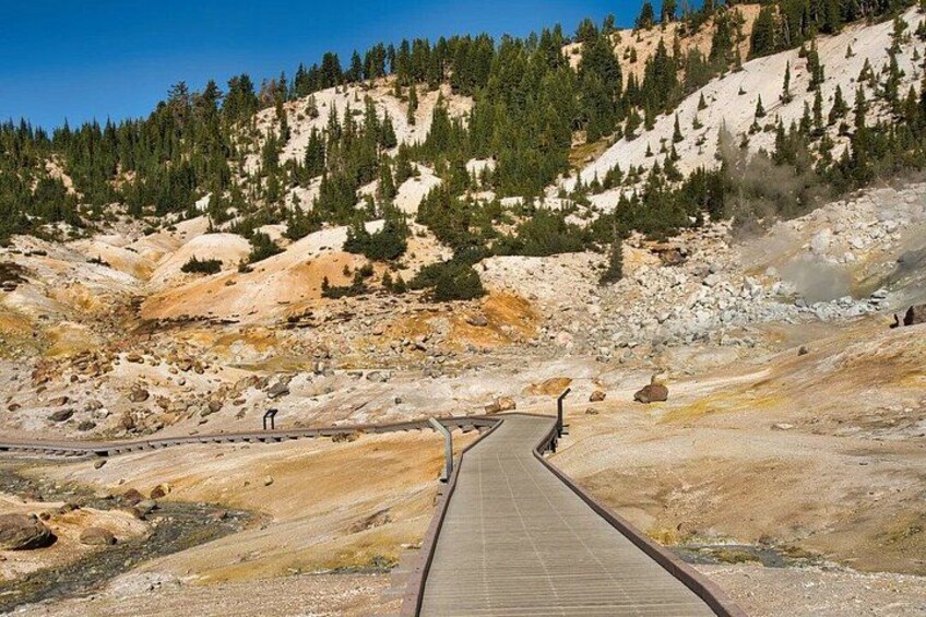 A paved walkway leading through a rocky landscape with sparse vegetation and a distant mountain. 4