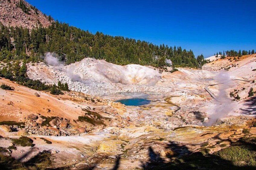 A geothermal area with a hot spring, mineral deposits, and forested hills. 5
