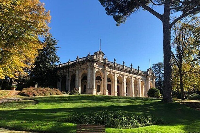 A historic building with arched windows and a central tower, surrounded by a well-maintained lawn and trees. 2