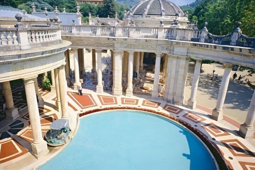 A large pool with a fountain, surrounded by classical architecture and a dome structure in the background. 1