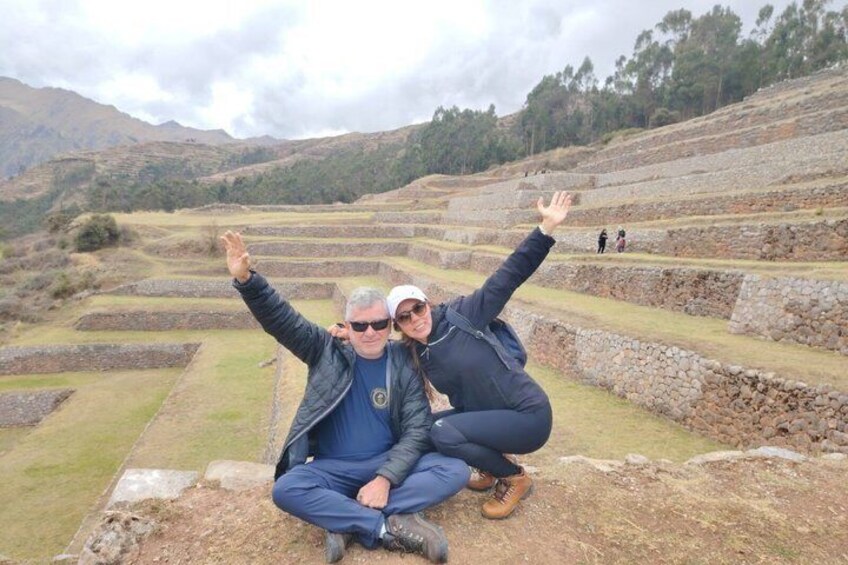 Two people posing in front of terraced fields with mountains in the background. 4