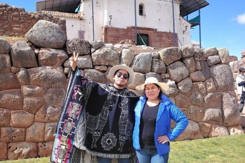Two people in front of a stone wall with a building in the background. 5