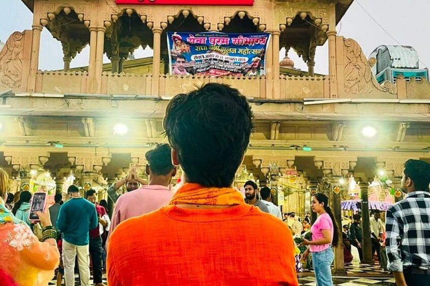 A crowd at a temple with a large illuminated sign. 4