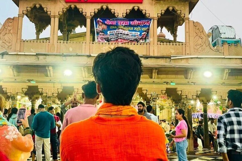 A crowd at a temple with a large illuminated sign. 4