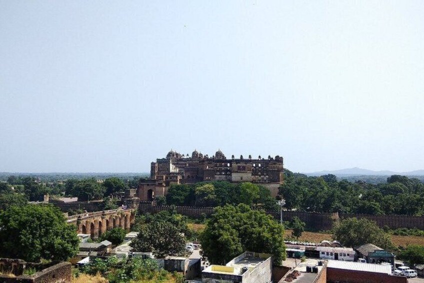 A historic fort with a large central tower, surrounded by lush greenery and a clear sky. 3