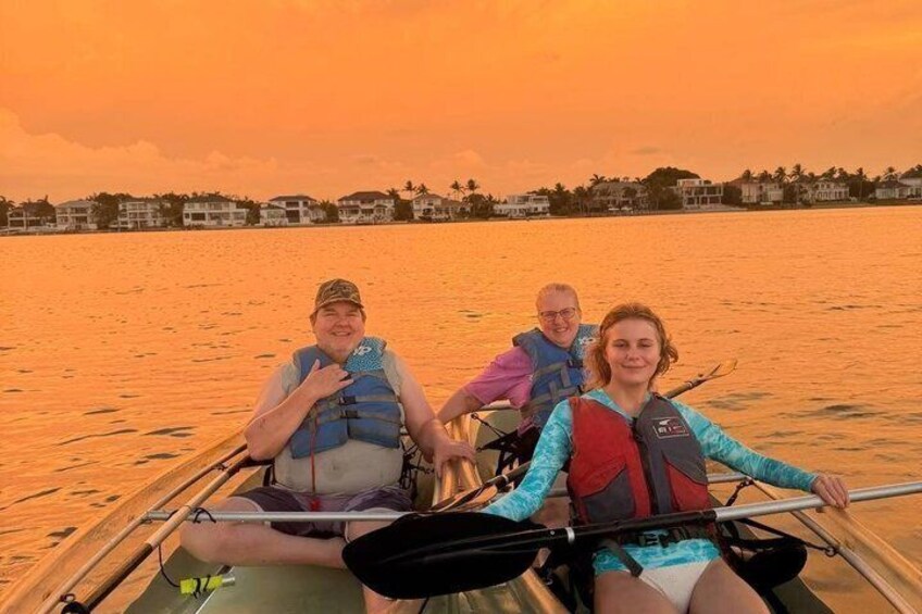 A group of people in a boat on a body of water during sunset. 1