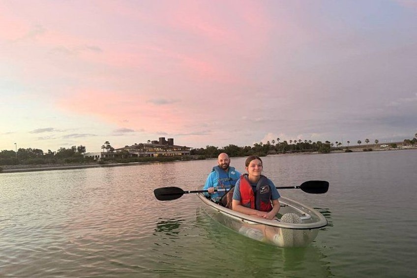 Two people kayaking on a calm river with a sunset in the background. 3