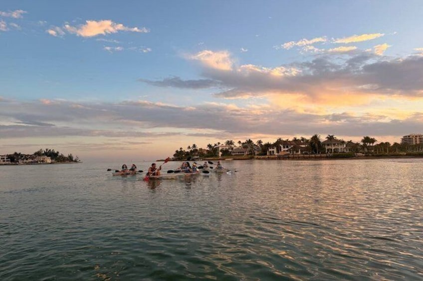 A sunset over a calm body of water with people kayaking. 4