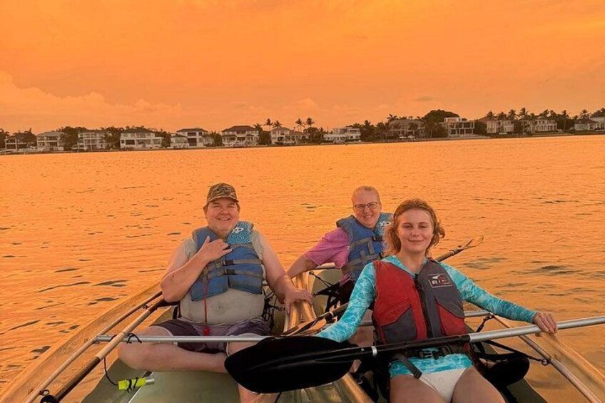 A group of people in a boat on a body of water during sunset. 1