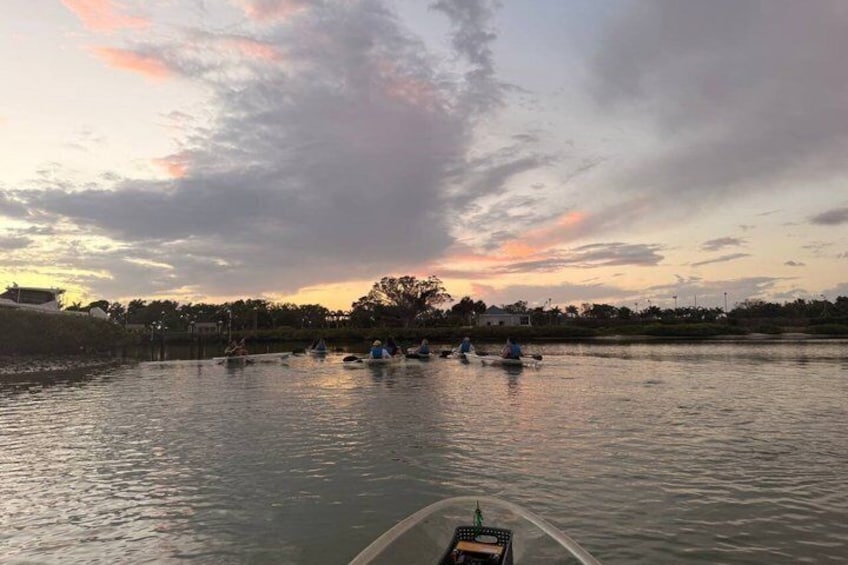 A calm river with several boats and canoes, a boat in the foreground, and a sunset sky. 5