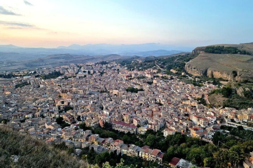 A panoramic view of a densely populated city with a mix of historical and modern architecture, surrounded by rolling hills and distant mountains. 2