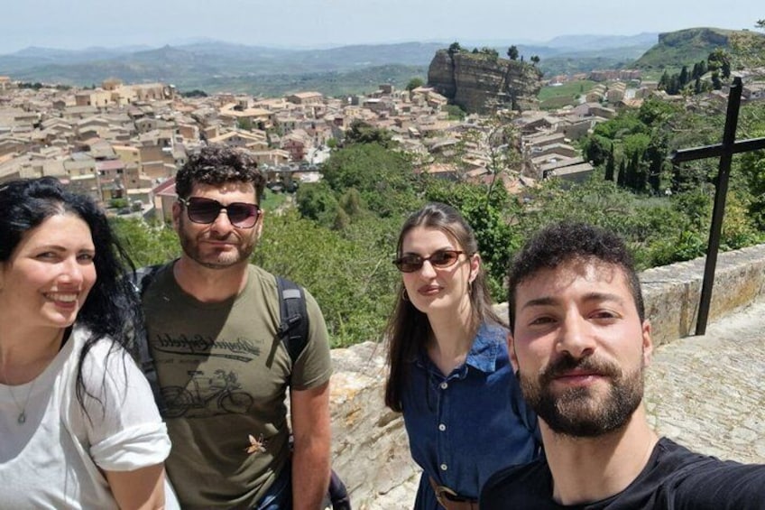A group of people standing on a stone wall overlooking a historic town with ancient ruins and a clear sky. 3