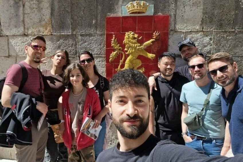 A group of people in front of a building with a lion emblem and a crown. 4