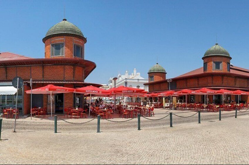 A seaside restaurant with red umbrellas and brick architecture. 3
