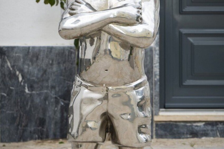 A metallic sculpture of a person with arms crossed. 5