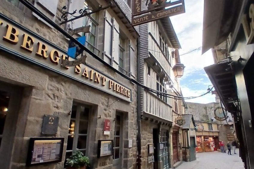 Una calle estrecha con edificios, uno con un letrero que dice 'BERGE SAINT PIERRE'. 3