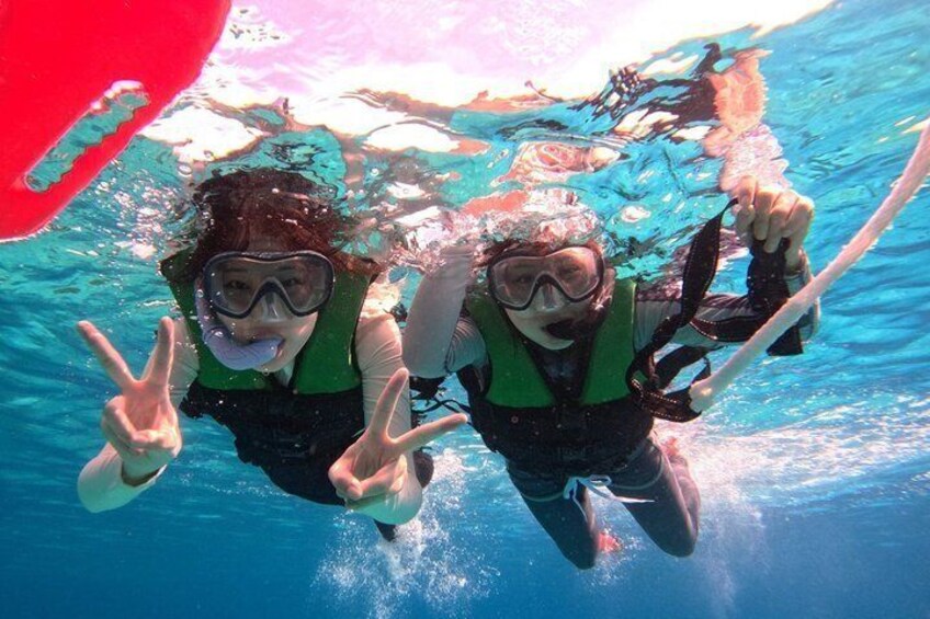 Two people scuba diving underwater, wearing green life vests and snorkels. 1