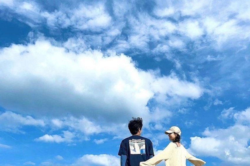 Two people standing with their backs to the camera, facing a sky filled with clouds. 4
