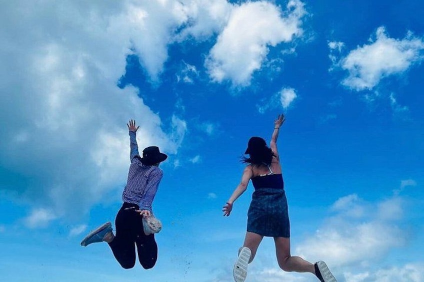 Two people jumping against a blue sky with clouds. 5