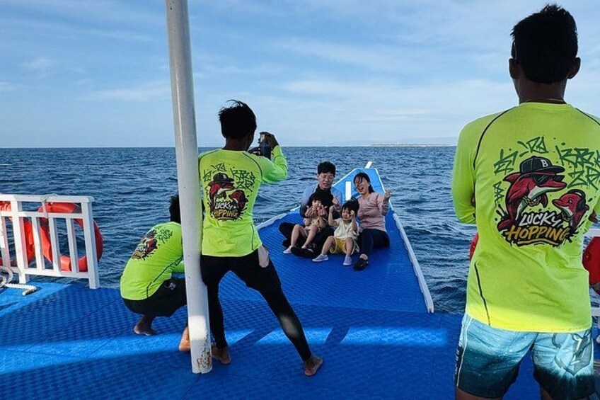 A group of people on a boat with a blue deck, some wearing bright yellow shirts, and a lifebuoy visible on the left. 2