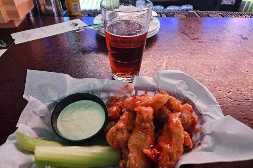 A basket of fried chicken wings with celery and a small bowl of dipping sauce, accompanied by a glass of iced tea. 3