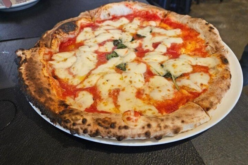 A pizza with a thick crust, topped with cheese and basil, on a white plate. 5