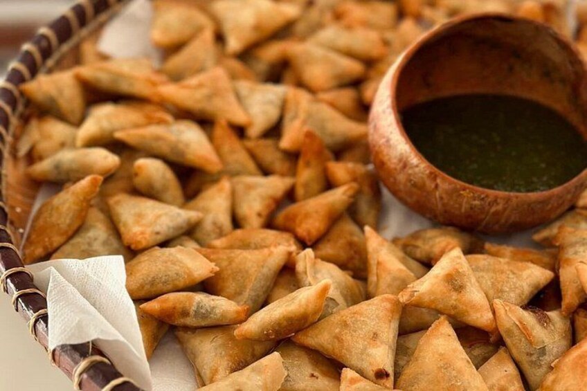 A basket of samosas with a dipping sauce. 3