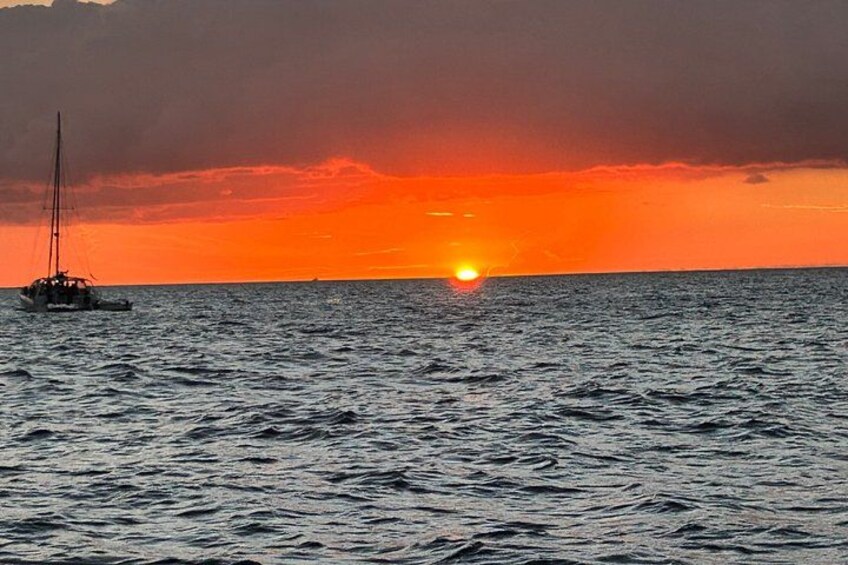 A sunset over the ocean with a sailboat. 4