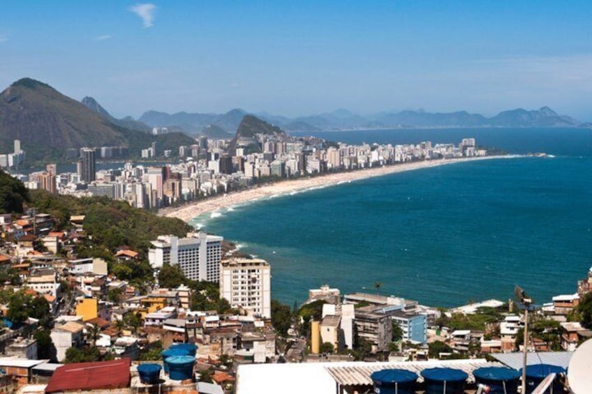 A coastal cityscape with a beach, mountains, and a dense urban area. 1