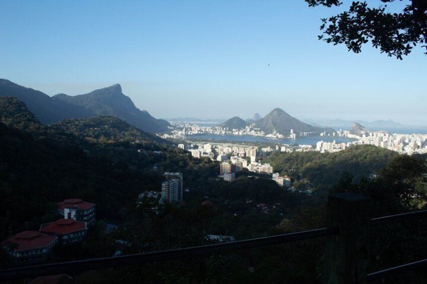 A cityscape with mountains in the background, a dense urban area in the middle, and a red-roofed building in the foreground. 3
