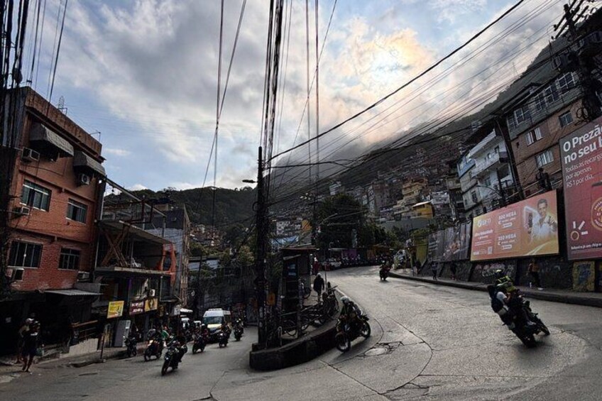 A busy urban street with multiple motorcycles, a construction site, and buildings with advertisements. 2