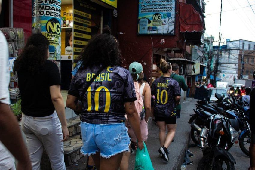 People walking on a street, some wearing sports jerseys. 1