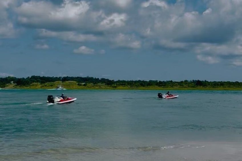 Two jet skis on a calm body of water with a distant shoreline. 4