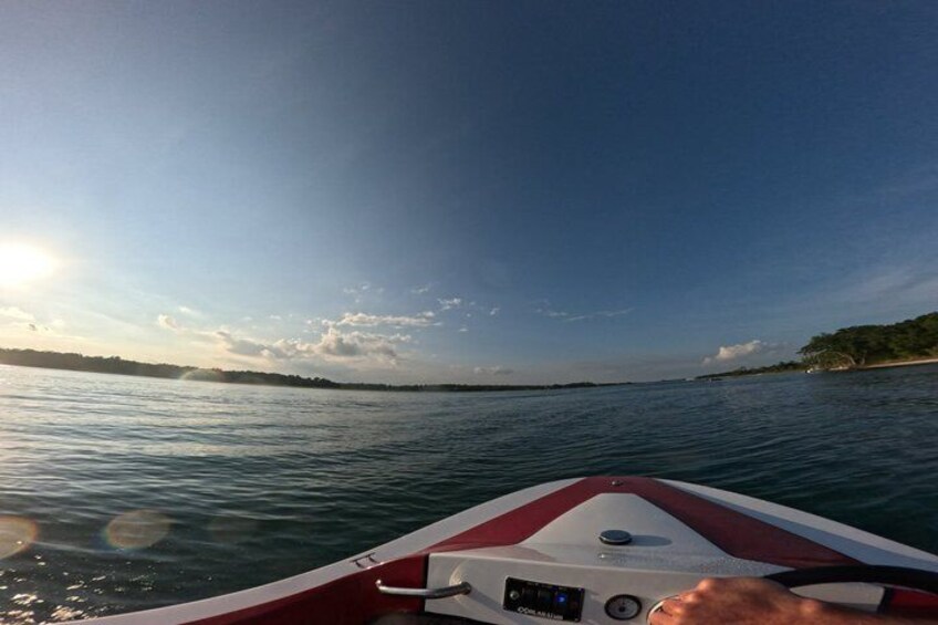 A boat on water with a clear sky and distant shoreline. 2