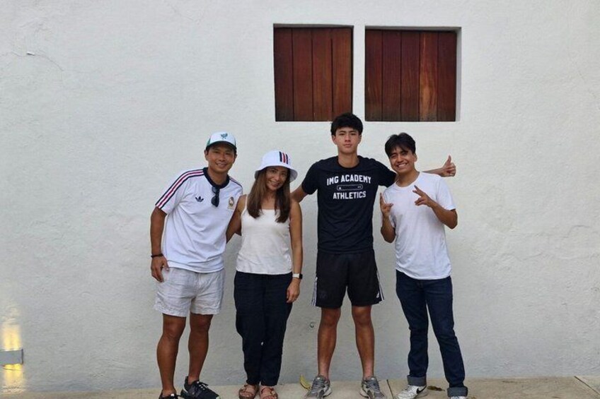 Four people standing in front of a white wall with a window. 2