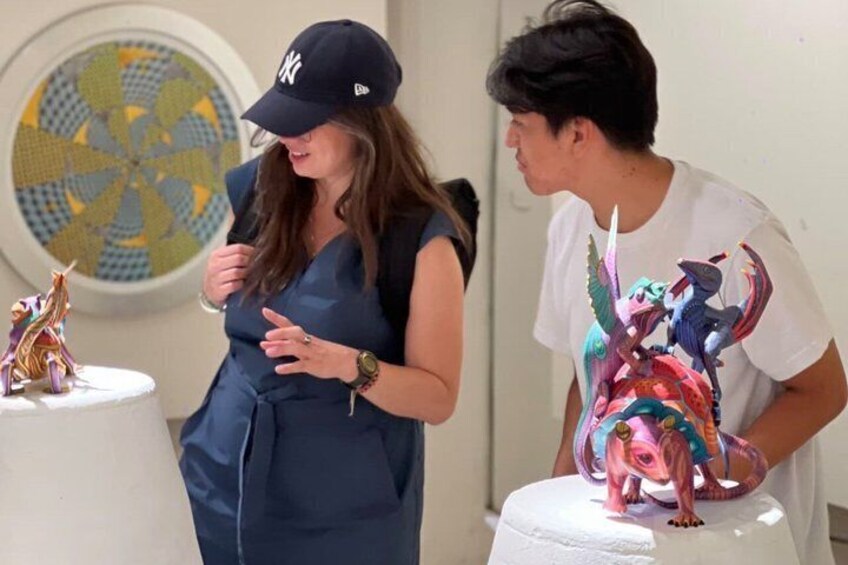 A person in a dark dress and cap standing next to a table with a dragon figurine. 4