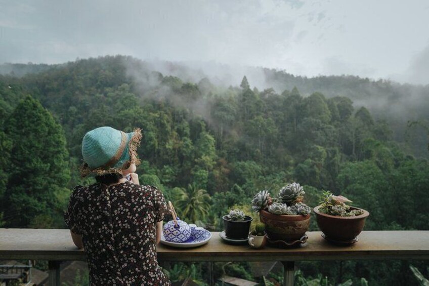 A person with a hat overlooking a forested area with mist. 3
