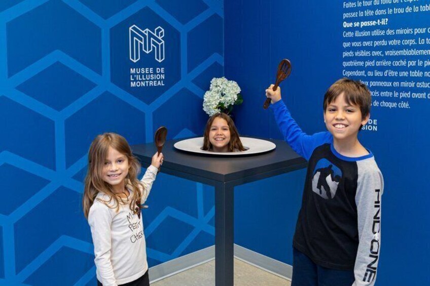 Three children at the Musée de l'Illusion Montreal, holding whisks and a plate with a flower. 4