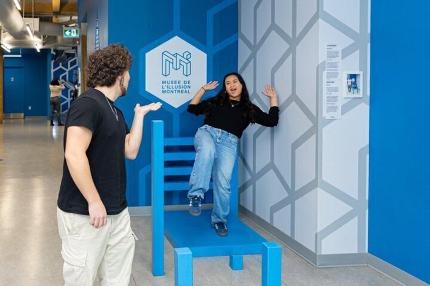 A person standing on a blue bench in front of a blue wall with a hexagonal sign. 5