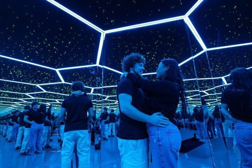 A geometric structure with people inside, illuminated by blue lighting. 2
