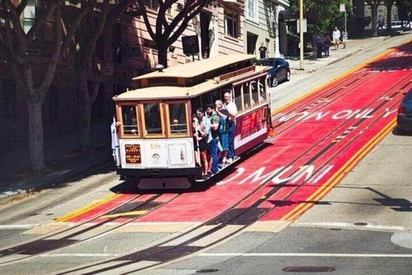 A cable car with passengers, a red bike lane, and a street with buildings. 5
