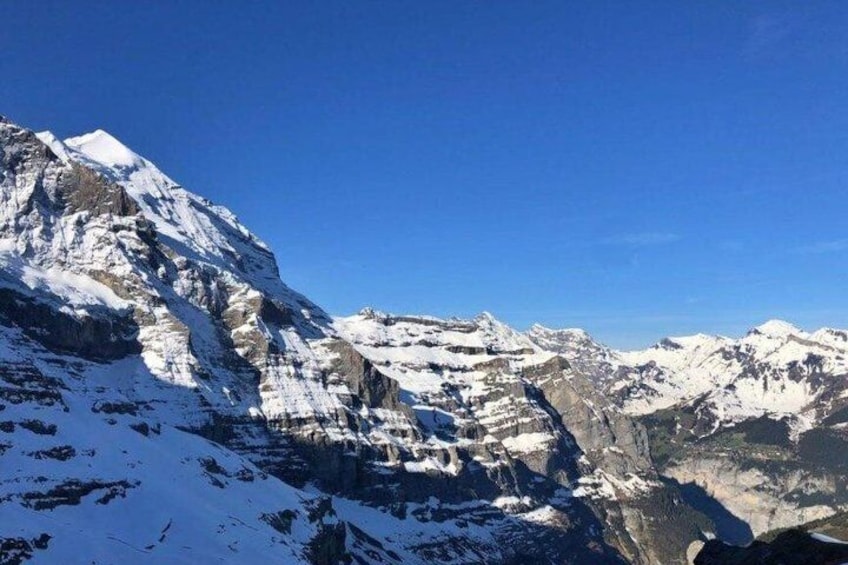 A snow-covered mountain range under a clear blue sky. 5