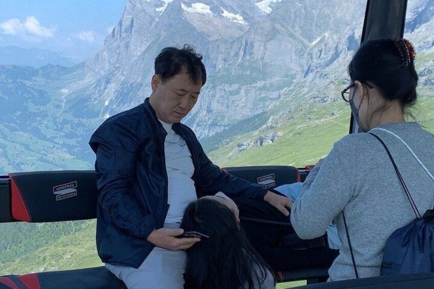 Two people seated on a bench with a mountainous landscape in the background. 2