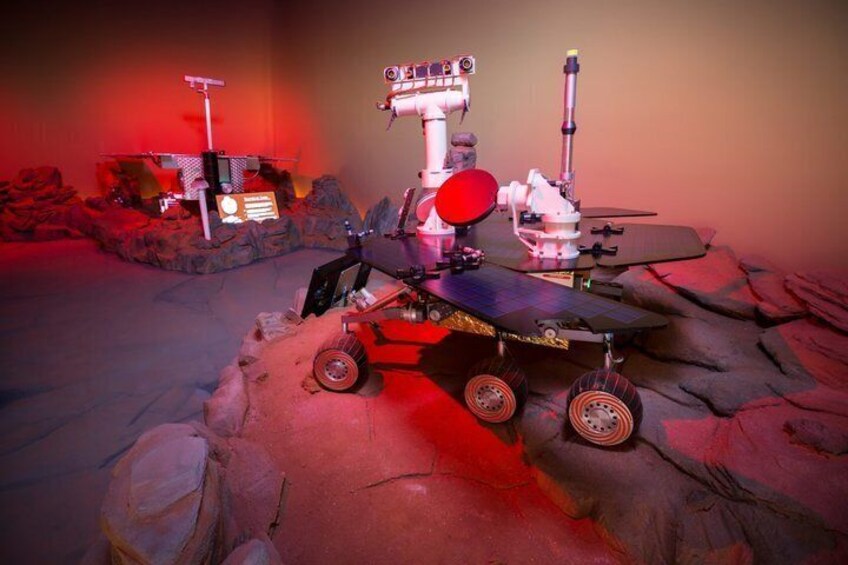 A rover on a rocky terrain with a solar panel and a communication dish. 3