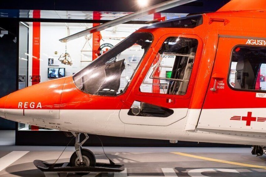 A red and white helicopter with 'REGA' and a medical cross symbol on its side. 4