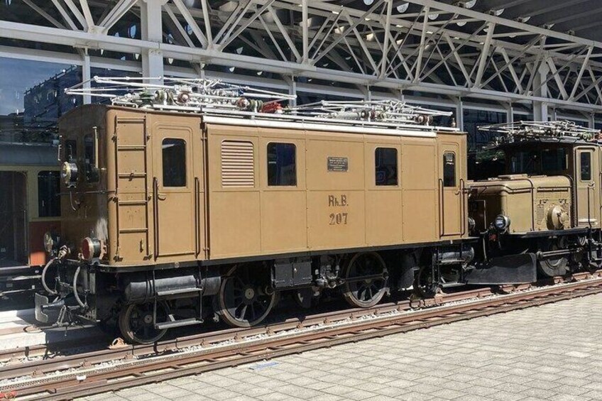 A vintage train with the number 207, parked at a station with a metal roof structure. 5