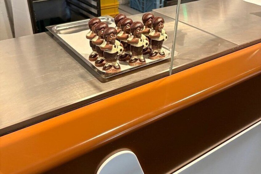 A tray of chocolate-covered figurines on a metallic surface. 5