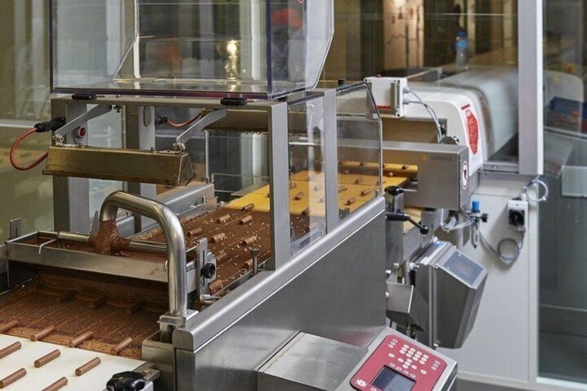 A chocolate tempering machine with a conveyor belt and a control panel. 2
